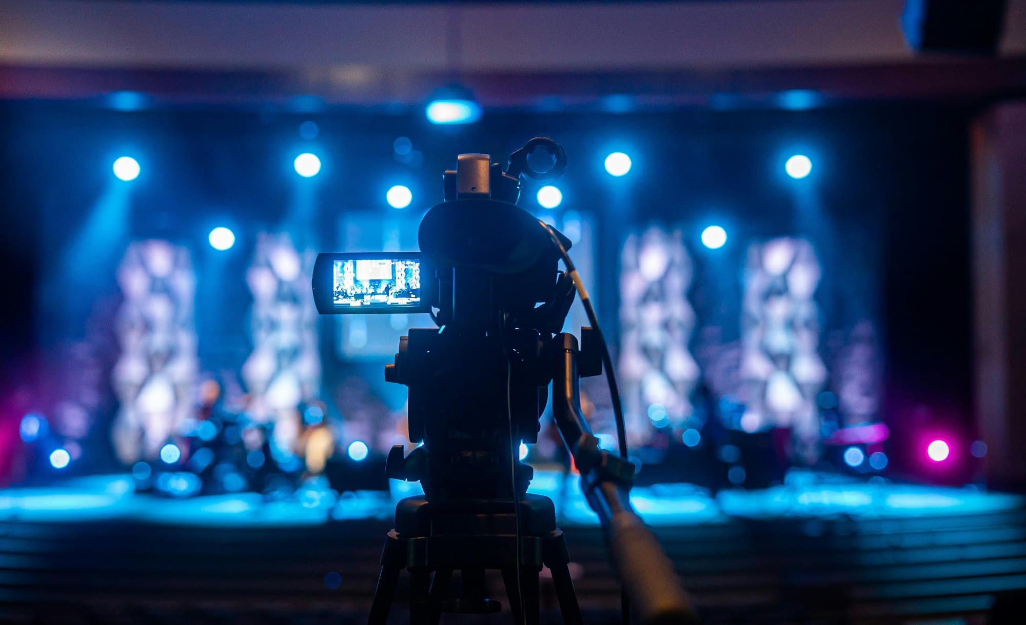 Live event camera facing a blue-lit stage